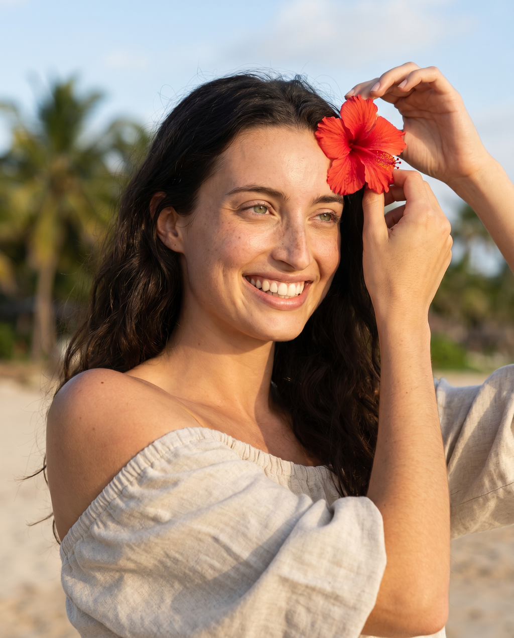Model placing hibiscus flower clip in hair